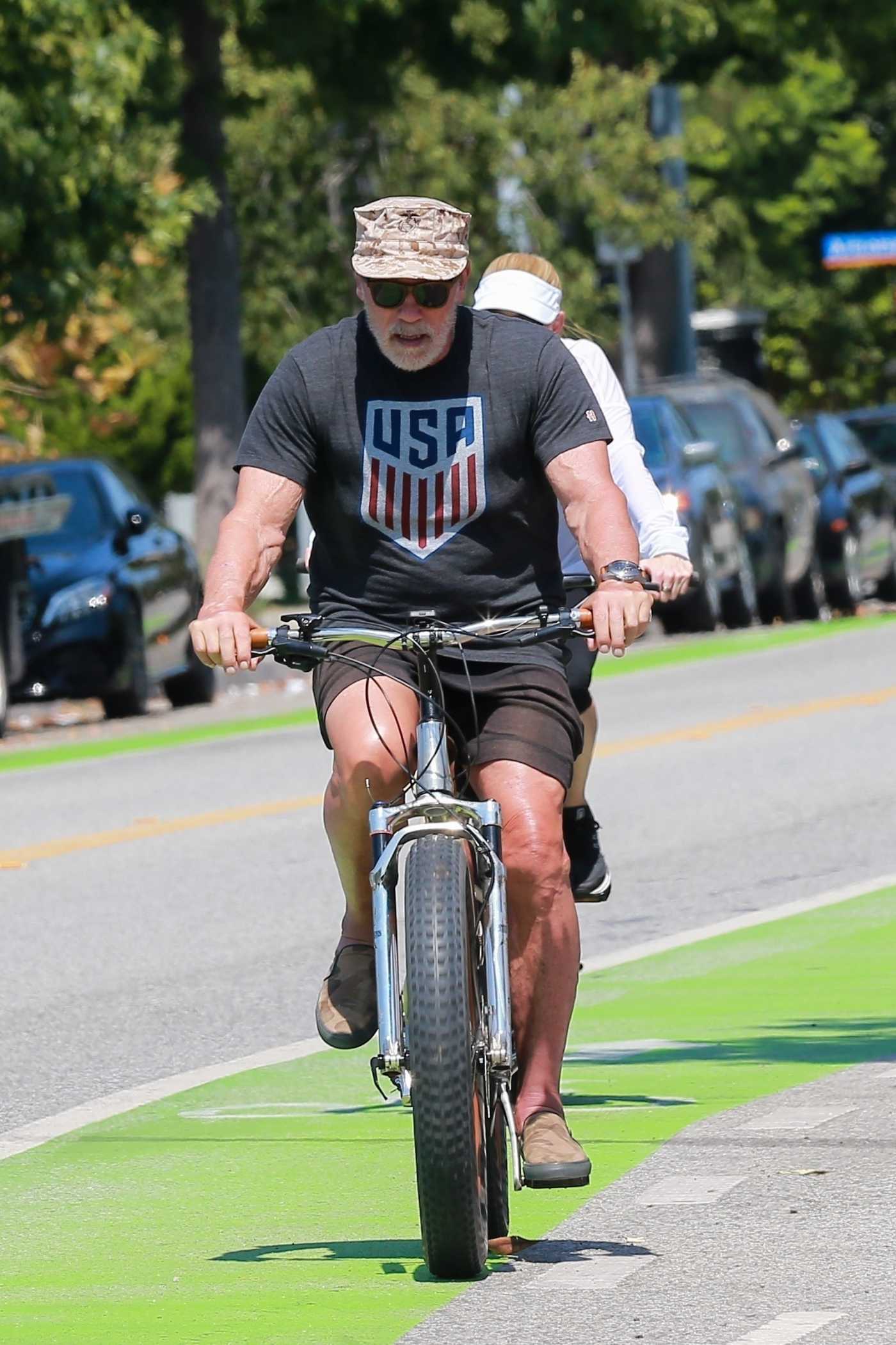 Arnold Schwarzenegger in a Black Tee Does a Bike Ride Out with Heather Milligan in Santa Monica 08/16/2020