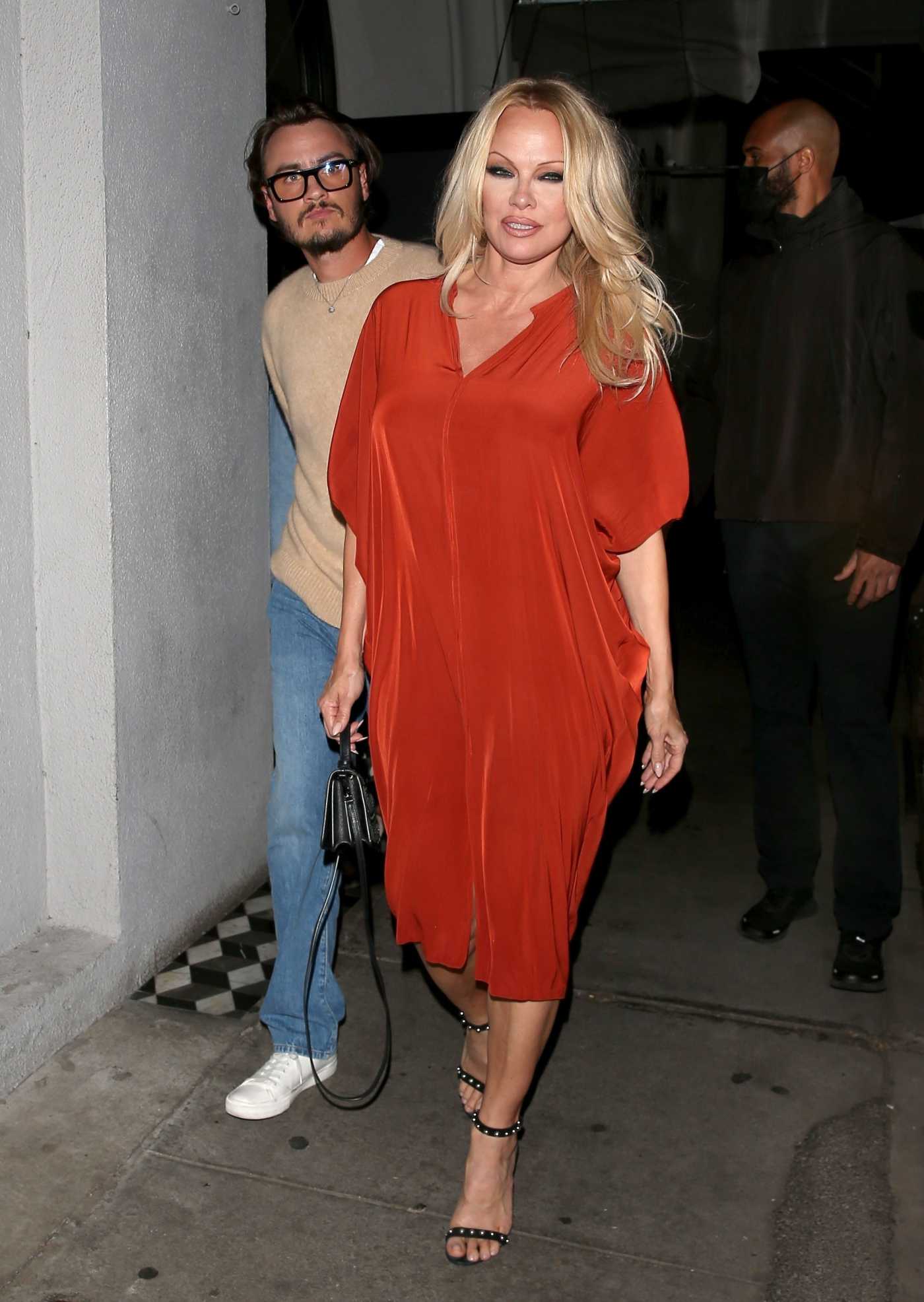Pamela Anderson in an Orange Dress Leaves Dinner with Son Brandon Lee at Craigs Restaurant in West Hollywood 03/06/2022