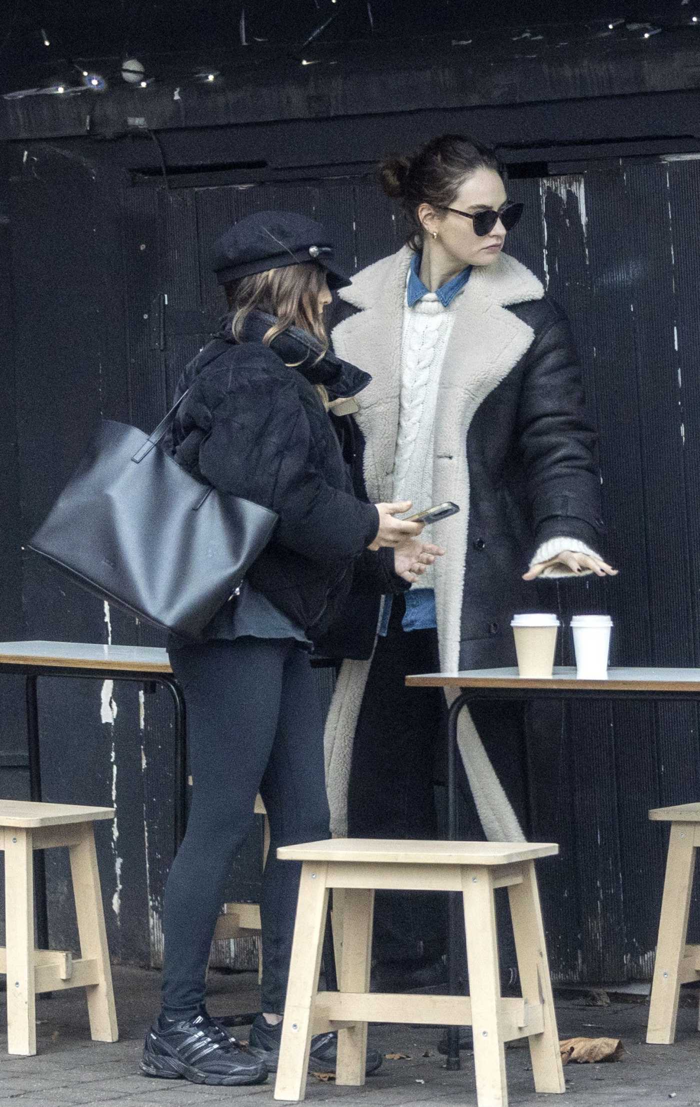 Lily James in a Black Sheepskin Coat Enjoys a Coffee with a Friend in London 01/26/2023