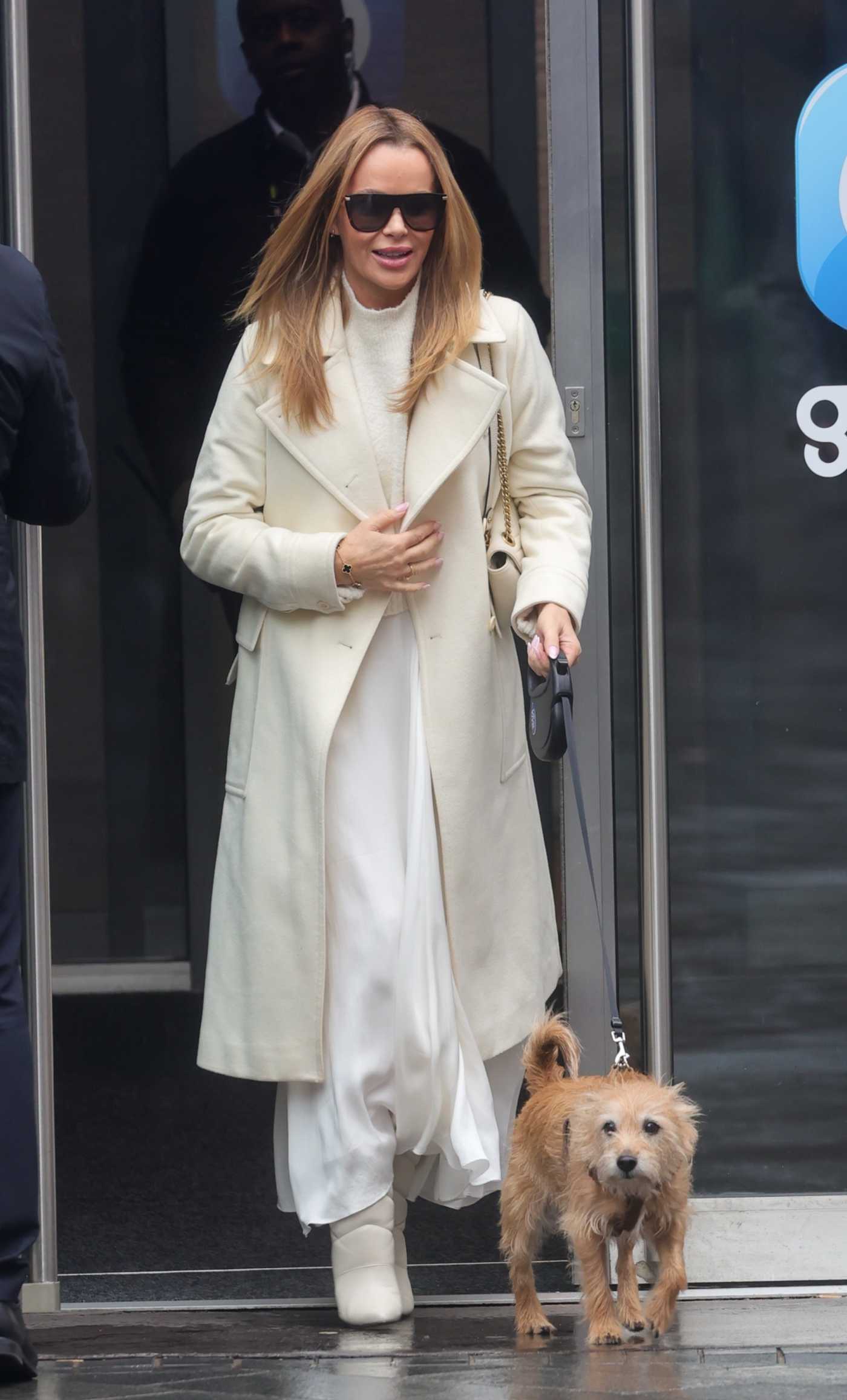 Amanda Holden in a White Coat Exits the Heart Radio with Her Pet Dog Rudie in London 03/17/2023