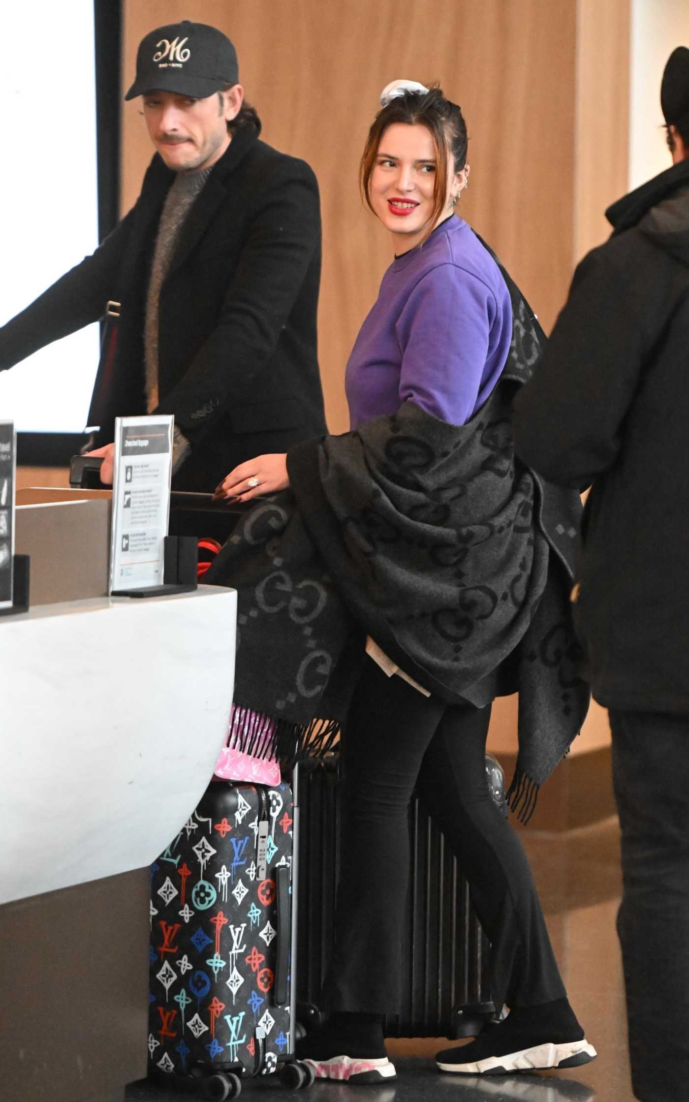 Bella Thorne in a Purple Sweatshirt Arrives with Mark Emms at JFK Airport in New York 02/16/2024
