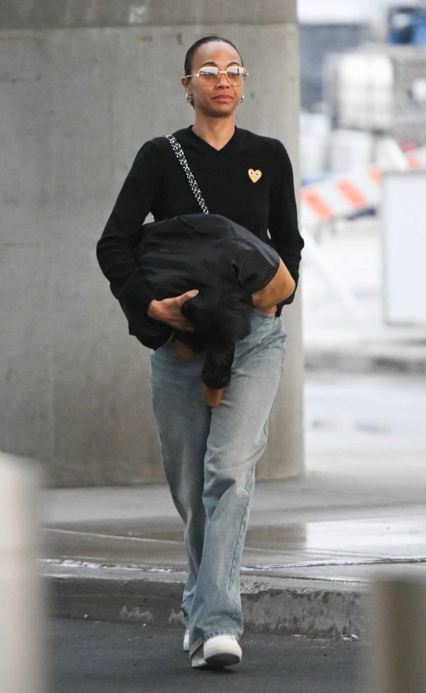 Zoe Saldana in a Black Jumper Arrives at JFK Airport in New York 03/27/2024