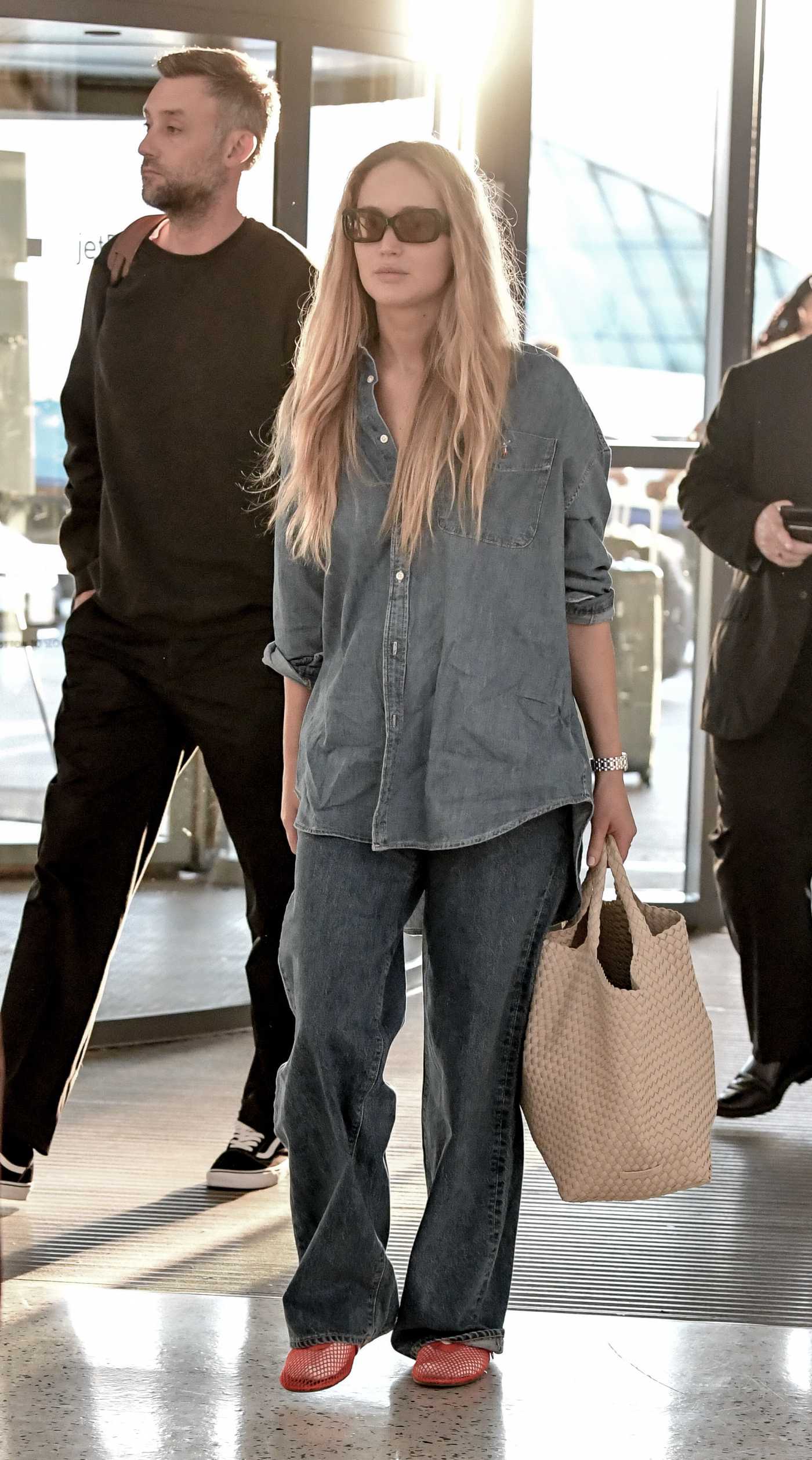 Jennifer Lawrence in a Denim Shirt Arrives at JFK Airport with Cooke Maroney in New York 06/01/2024
