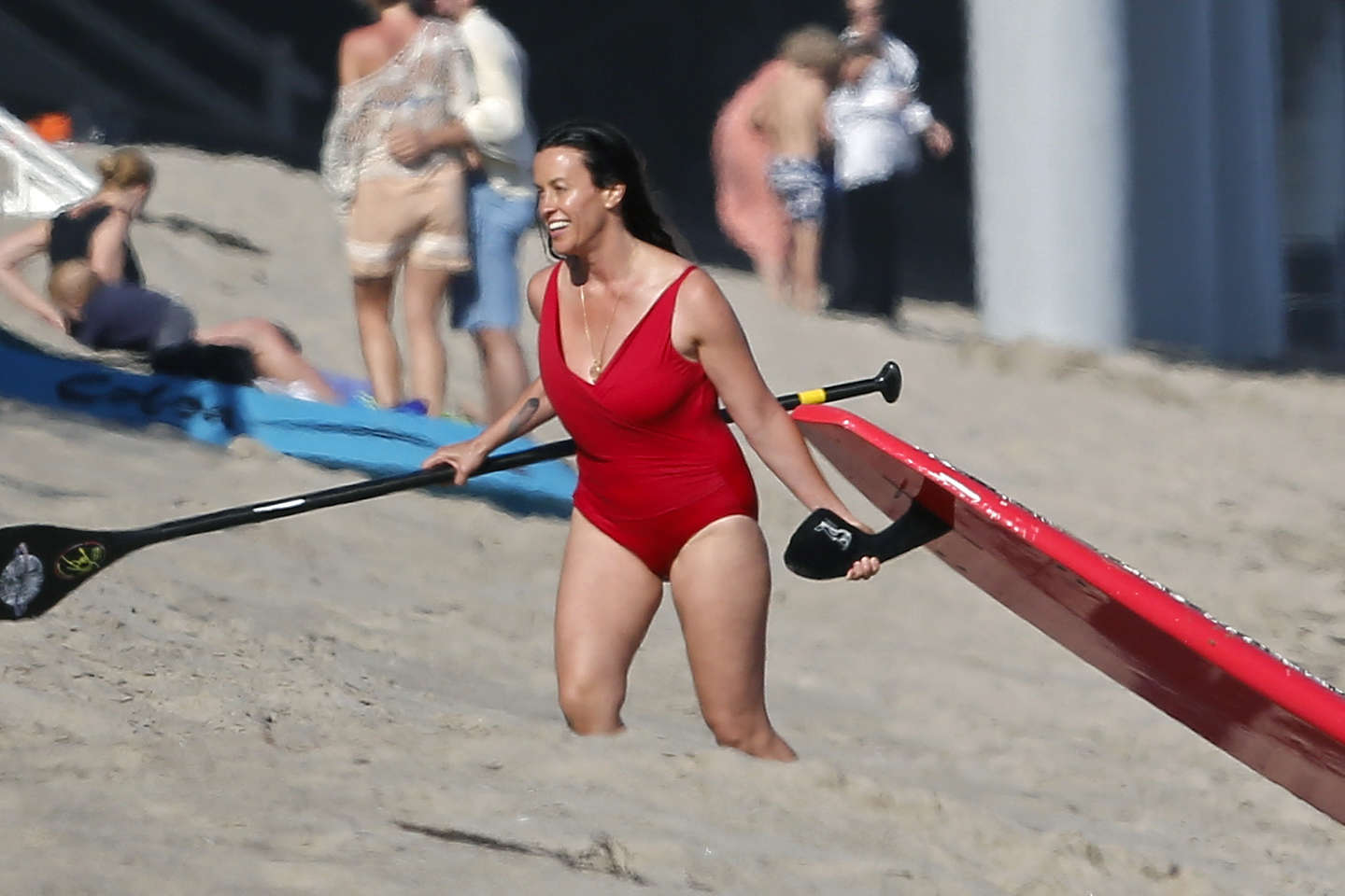 Alanis Morissette paddleboarding in red swimsuit